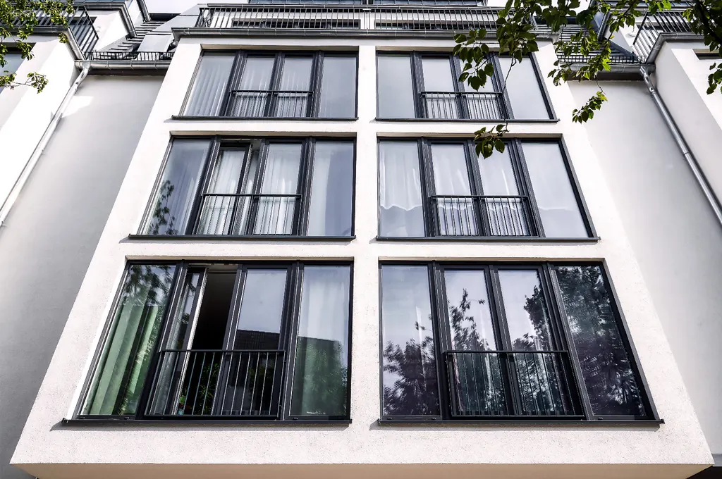 Fachada de un edificio residencial con grandes ventanales en color antracita